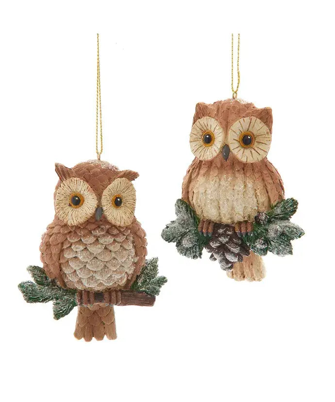 Two owl-shaped Christmas ornaments with greenery on a white background