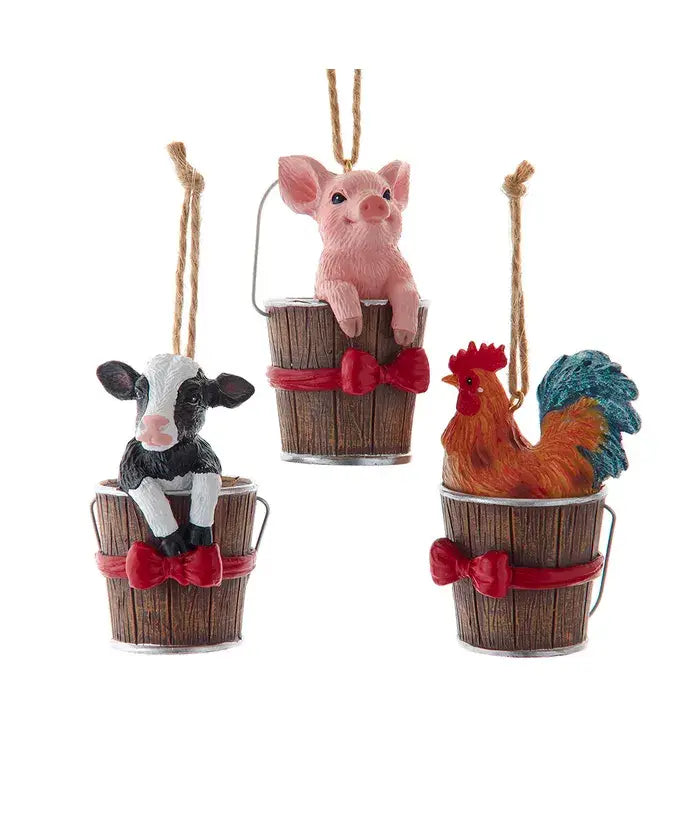 Assotment of three farm animal ornaments in wooden buckets on a white background